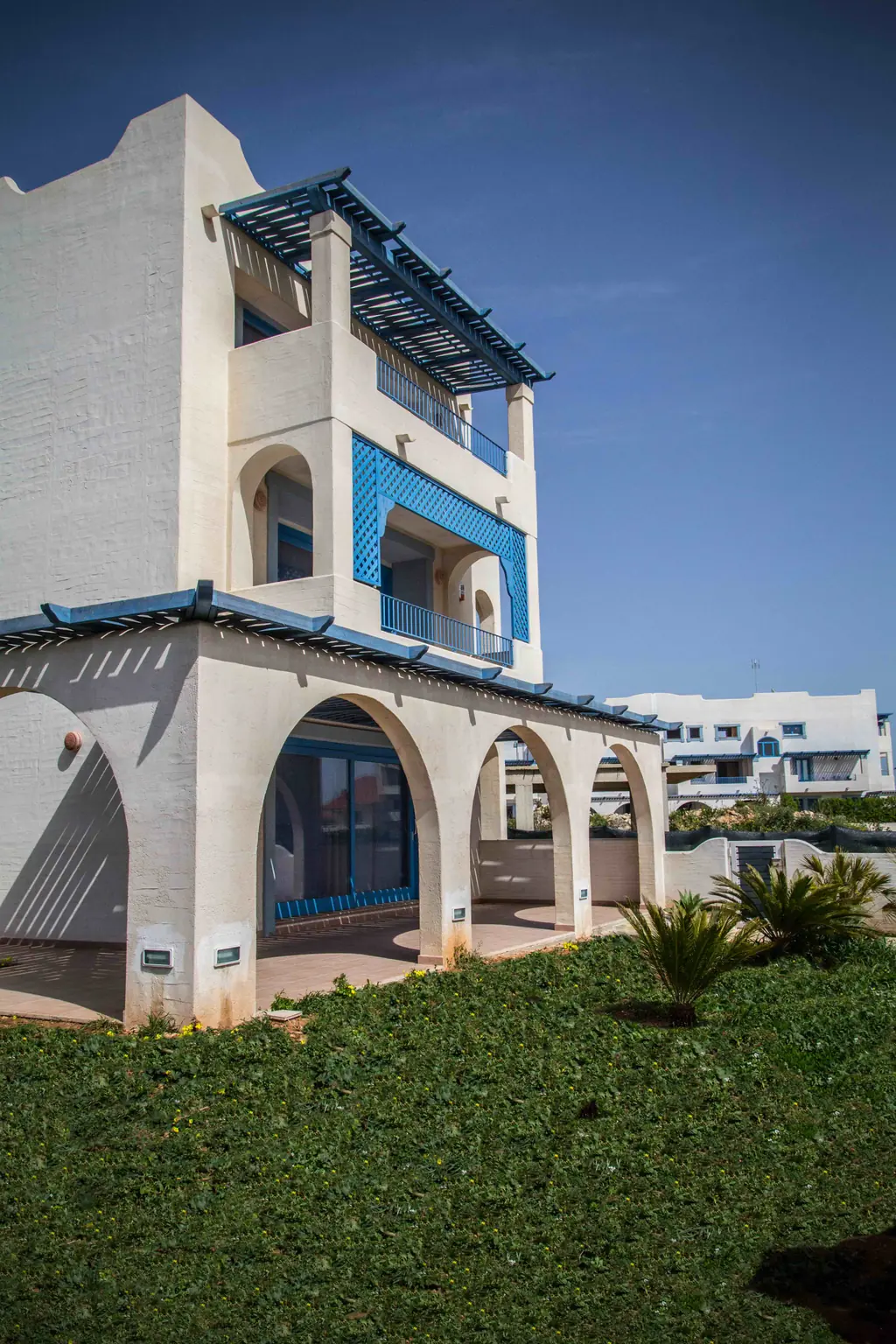 La torretta bianca del residence con gli archi e gli infissi blu, sotto il cielo sereno